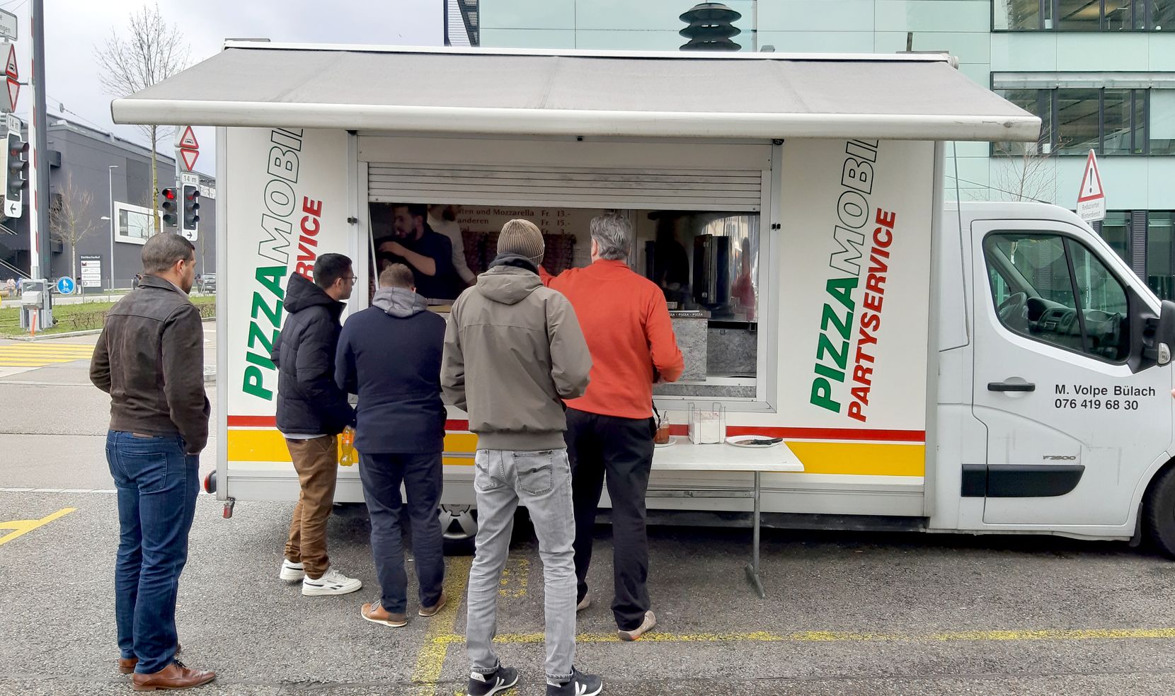 Ein Pizzamobil im Industriequartier, davor eine wartende Menschenmenge.